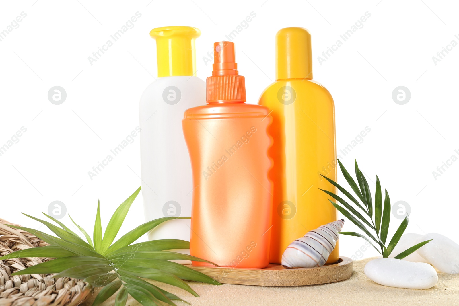 Photo of Different sun protection products, green leaves, stones and seashell on sand against white background