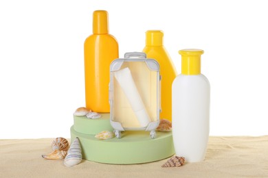 Different sun protection products and seashells on sand against white background