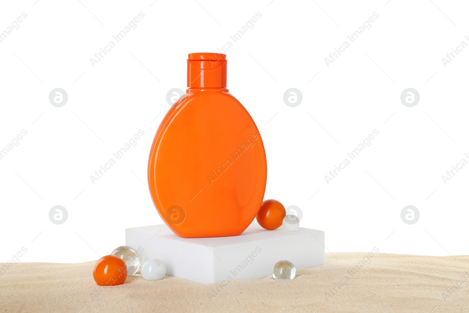 Photo of Bottle of sun protection product and decorative stones on sand against white background