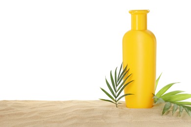 Bottle of sun protection product and green leaves on sand against white background