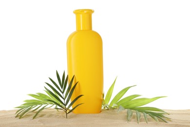 Photo of Bottle of sun protection product and green leaves on sand against white background