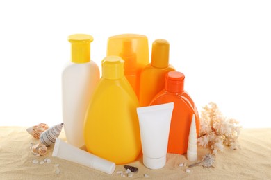 Different sun protection products, coral and seashells on sand against white background