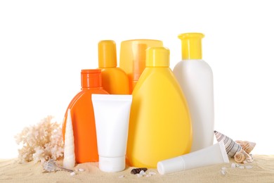 Different sun protection products, coral and seashells on sand against white background