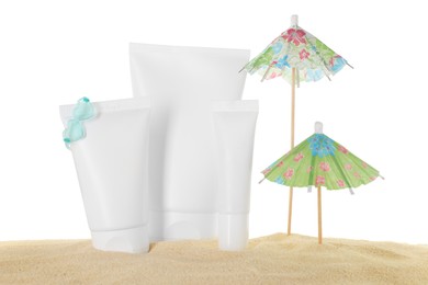 Photo of Tubes of sun protection product and small umbrellas on sand against white background