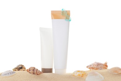 Photo of Tubes of sun protection product and seashells on sand against white background