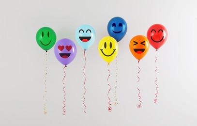 Image of Bright balloons with happy faces on light background