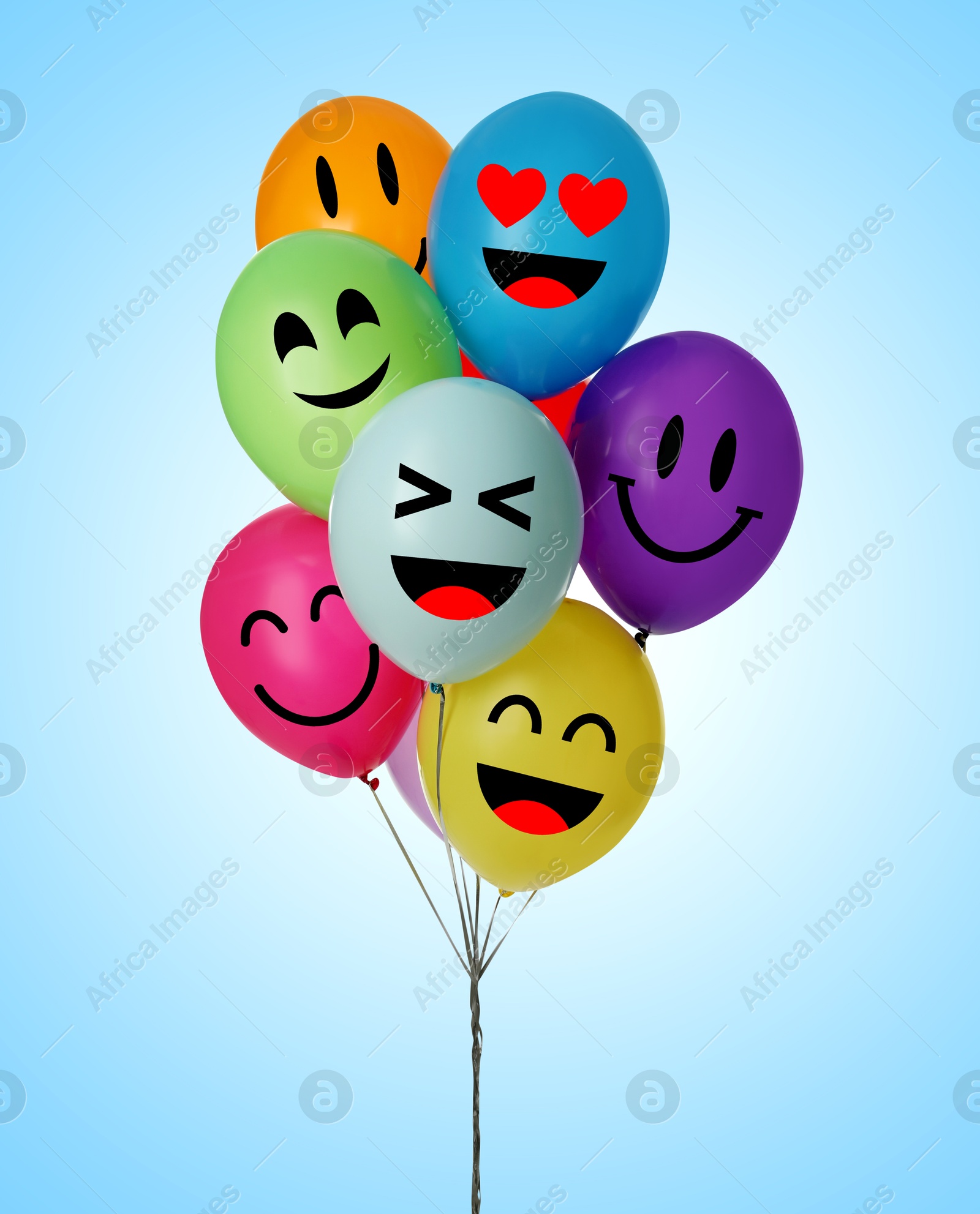 Image of Bright balloons with happy faces on light blue gradient background