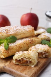 Photo of Tasty apple strudels with powdered sugar and mint on table, closeup