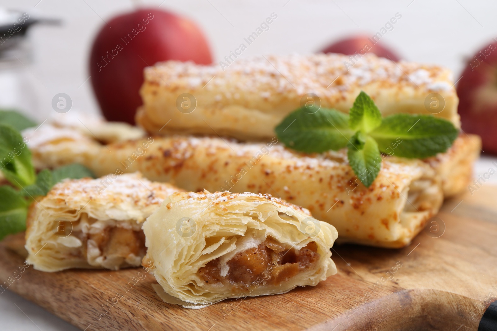 Photo of Tasty apple strudels with powdered sugar and mint on table, closeup