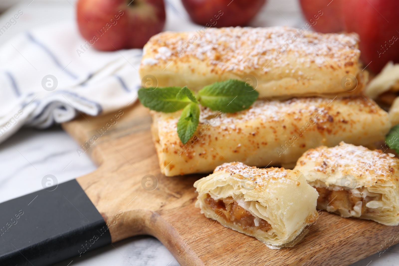 Photo of Tasty apple strudels with powdered sugar and mint on table, closeup