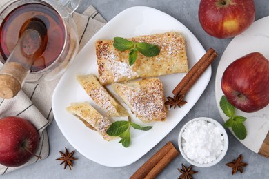 Tasty apple strudels served on light grey table, flat lay