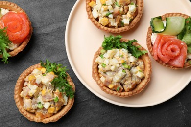 Photo of Tartlets with delicious fillings on black table, top view