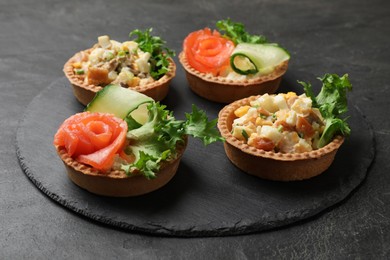 Photo of Tartlets with delicious fillings on black table, closeup