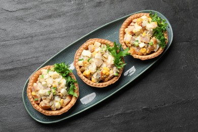Photo of Tartlets with delicious filling on black table, top view