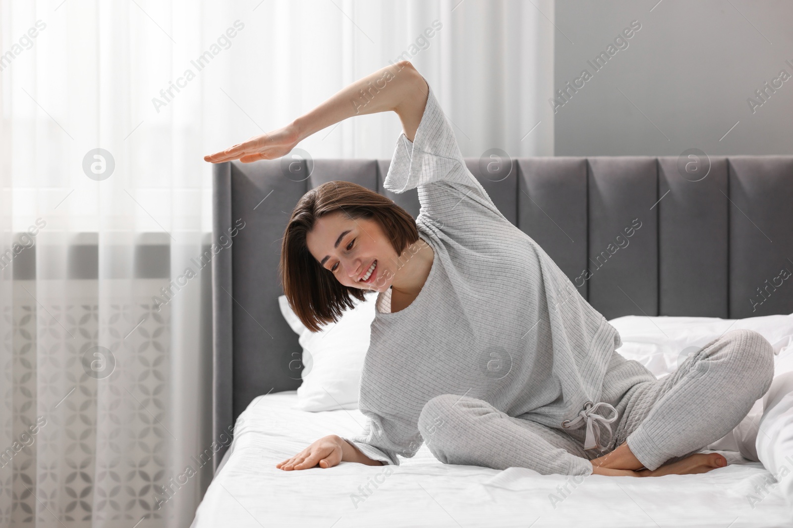 Photo of Young woman exercising on bed at home. Morning routine