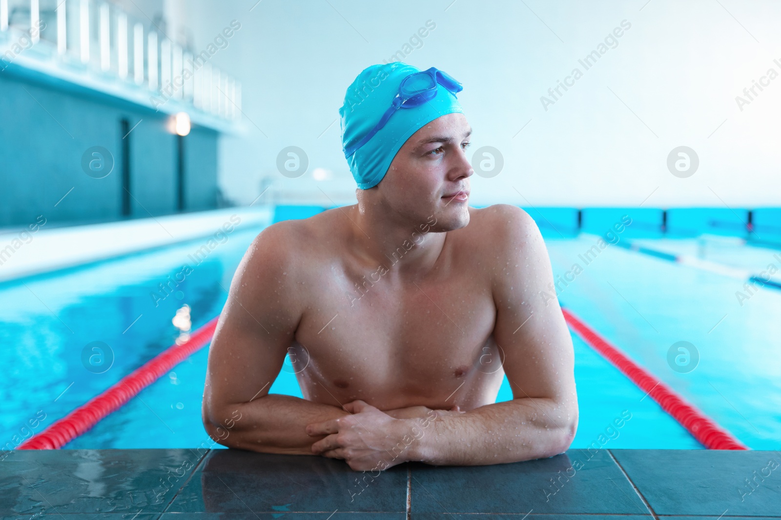 Photo of Young man with cap and goggles in swimming pool indoors