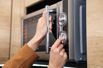 Woman turning on microwave at home, closeup