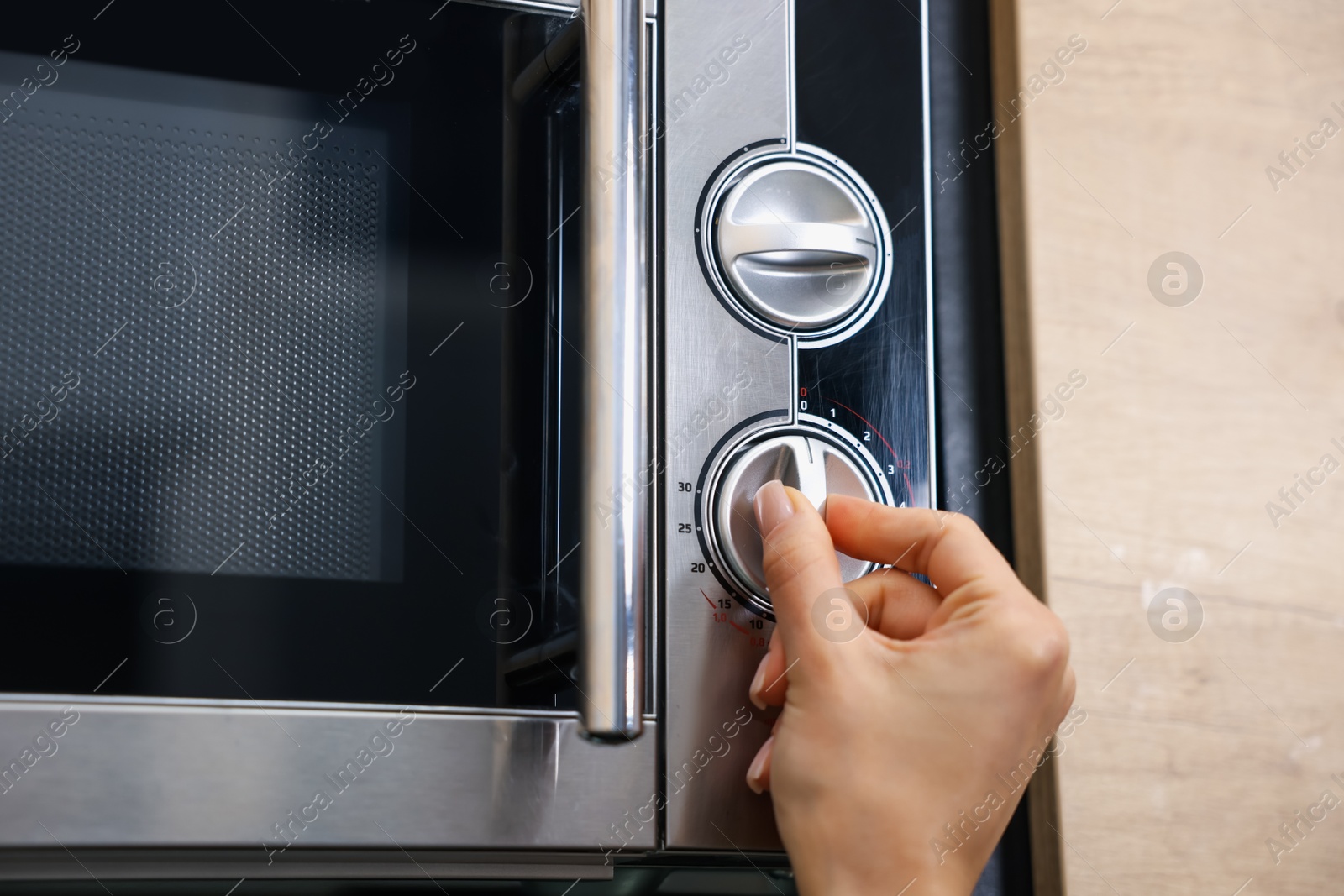 Photo of Woman turning on microwave at home, closeup