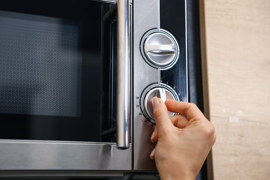 Woman turning on microwave at home, closeup