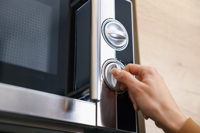 Photo of Woman turning on microwave at home, closeup