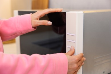 Woman turning on microwave at home, closeup