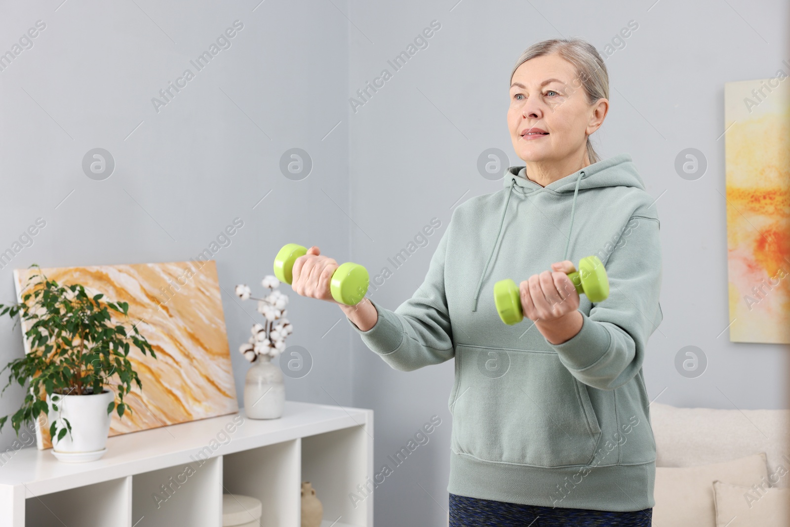 Photo of Elderly woman exercising with dumbbells at home