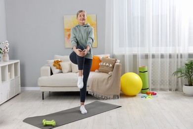 Photo of Smiling elderly woman doing exercise at home