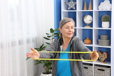 Elderly woman exercising with fitness elastic band at home