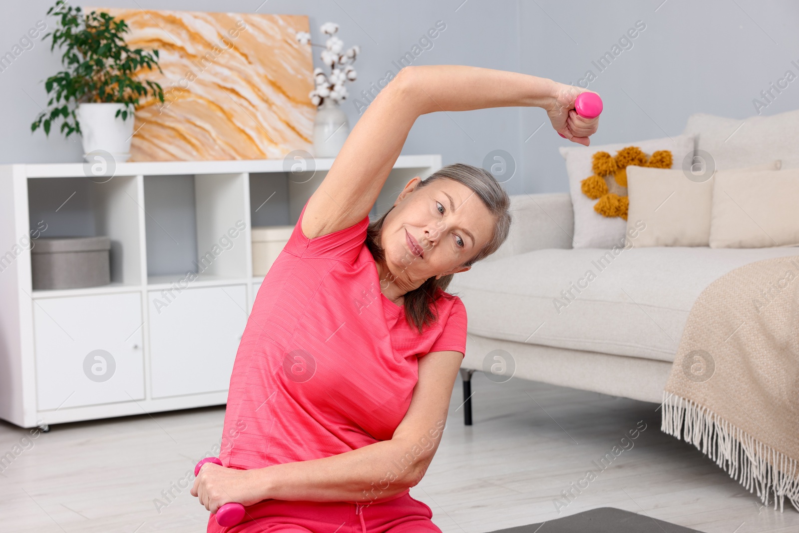 Photo of Elderly woman exercising with dumbbells at home