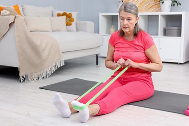 Elderly woman exercising with fitness elastic band at home