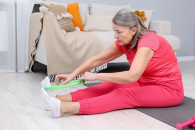 Elderly woman exercising with fitness elastic band at home