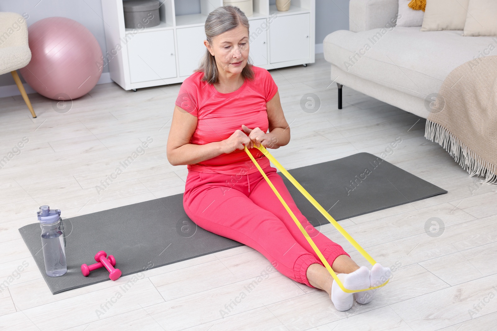 Photo of Elderly woman exercising with fitness elastic band at home