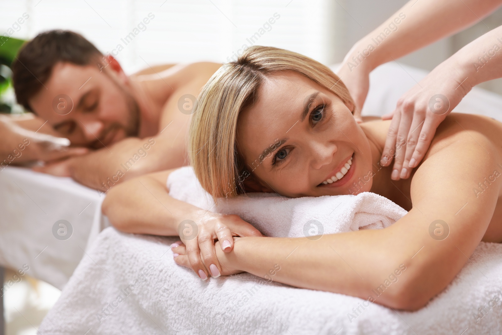 Photo of Happy couple receiving relaxing massage in spa salon, selective focus