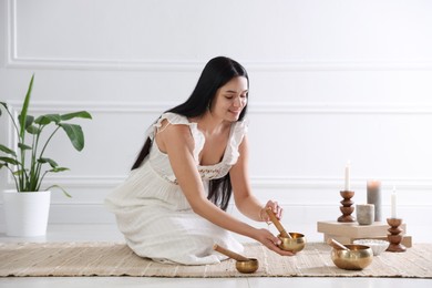 Woman with singing bowls on floor indoors