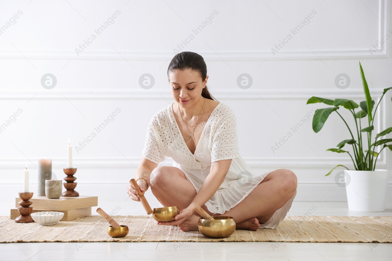 Photo of Woman with singing bowls on floor indoors