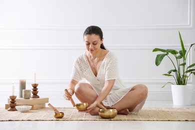 Woman with singing bowls on floor indoors