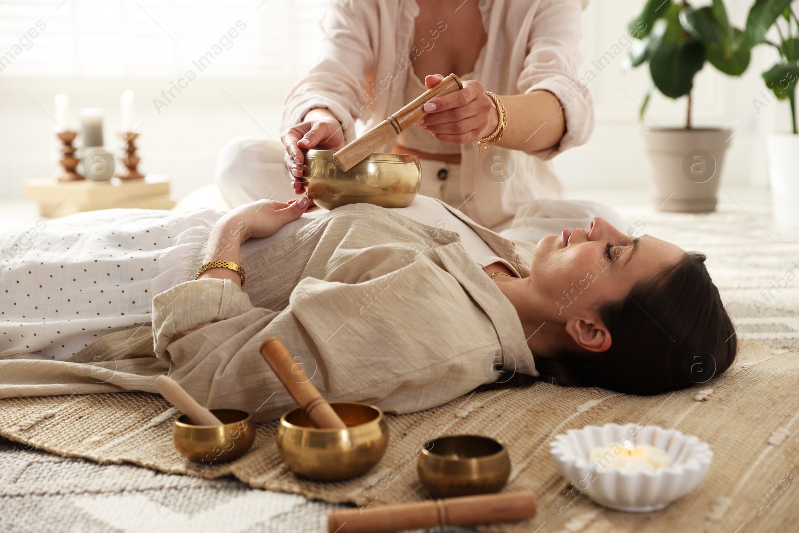 Photo of Woman undergoing singing bowl therapy lying on floor indoors