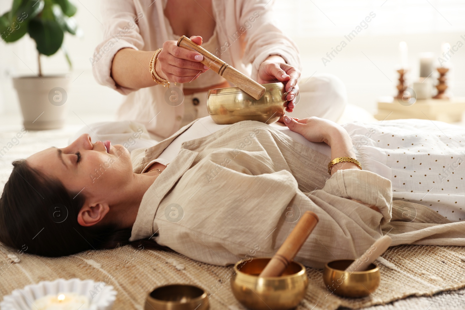 Photo of Woman undergoing singing bowl therapy lying on floor indoors