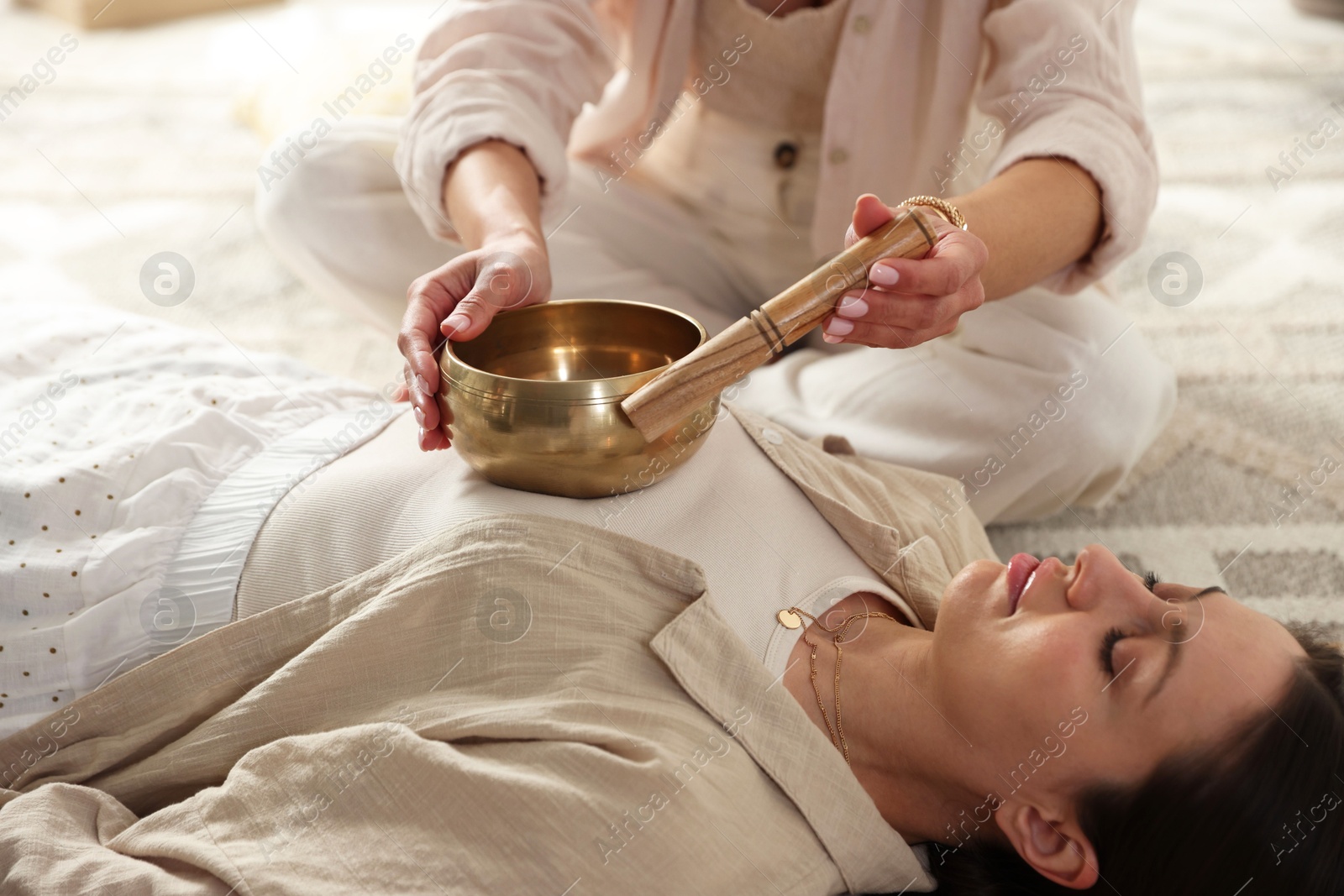 Photo of Woman undergoing singing bowl therapy lying on floor indoors