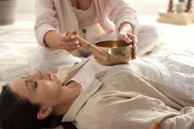 Photo of Woman undergoing singing bowl therapy lying on floor indoors