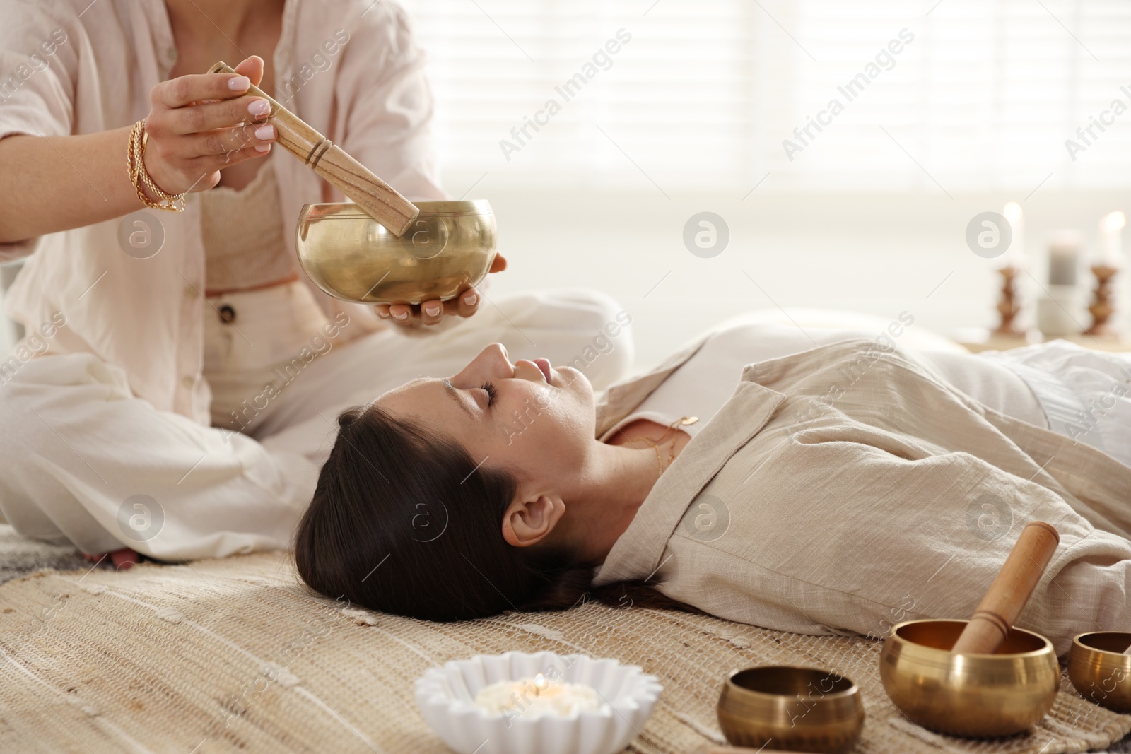 Photo of Woman undergoing singing bowl therapy lying on floor indoors