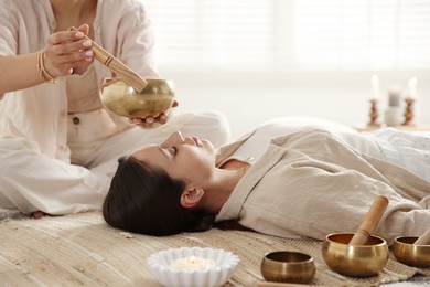 Woman undergoing singing bowl therapy lying on floor indoors