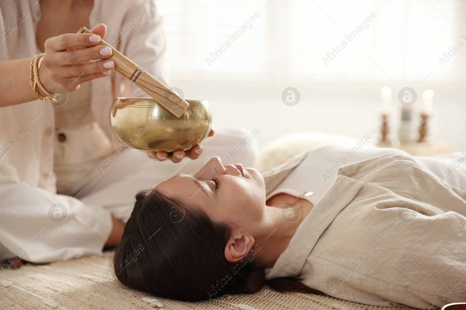 Photo of Woman undergoing singing bowl therapy lying on floor indoors