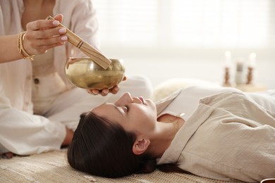 Photo of Woman undergoing singing bowl therapy lying on floor indoors