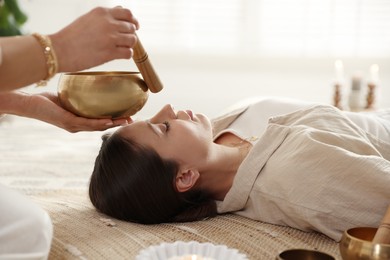 Photo of Woman undergoing singing bowl therapy lying on floor indoors