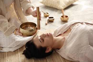 Woman undergoing singing bowl therapy lying on floor indoors