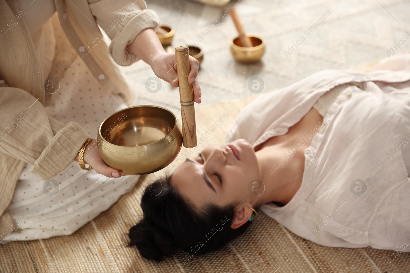 Photo of Woman undergoing singing bowl therapy lying on floor indoors