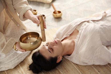 Woman undergoing singing bowl therapy lying on floor indoors