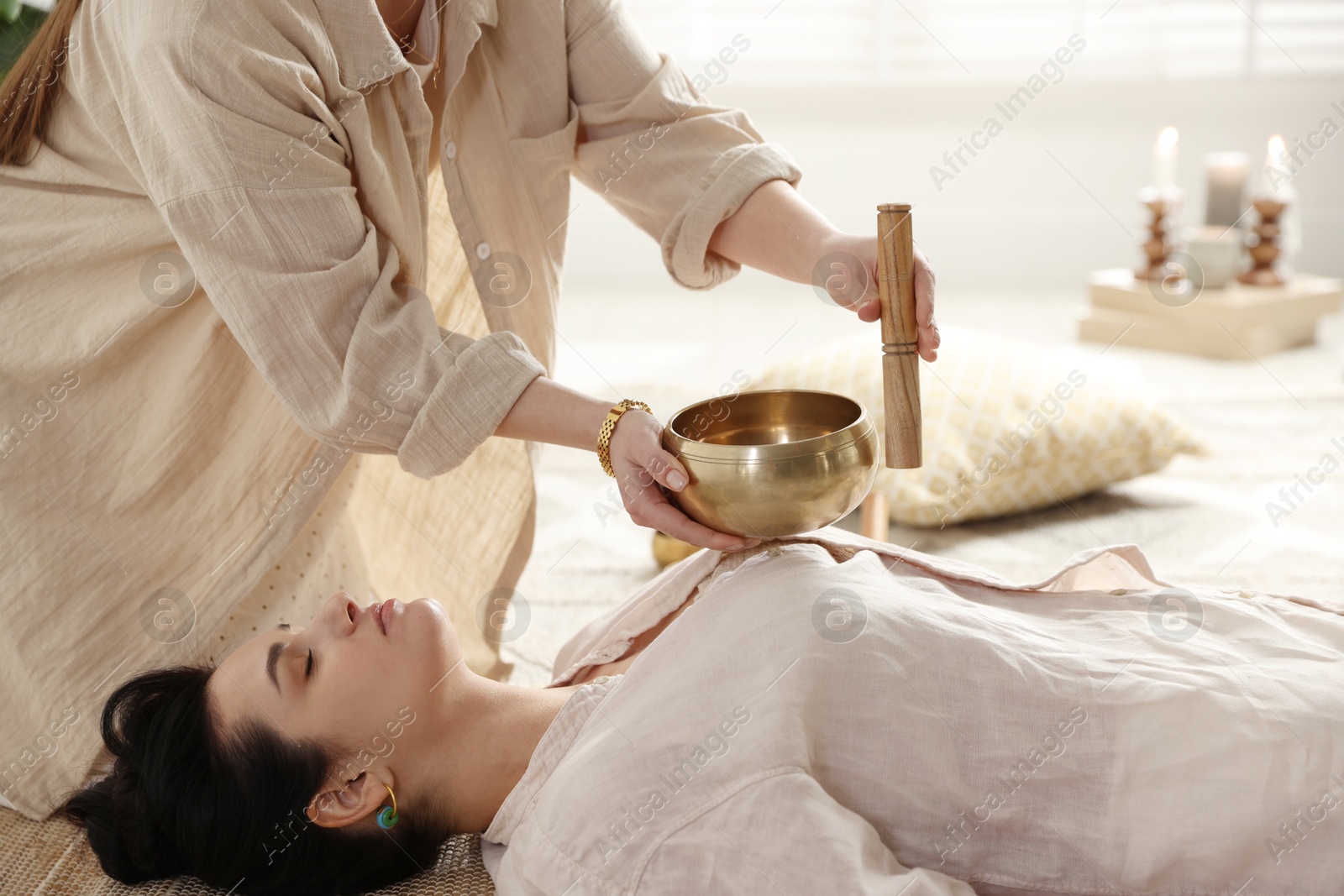 Photo of Woman undergoing singing bowl therapy lying on floor indoors