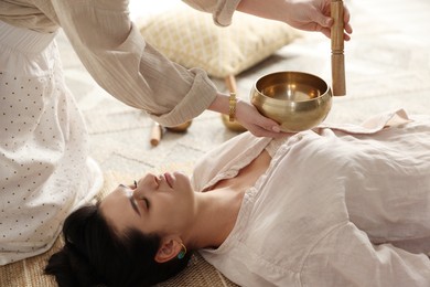 Woman undergoing singing bowl therapy lying on floor indoors